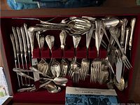 Top-down view of flatware arranged in red velvet slots inside wood case