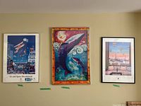Photo of three framed posters hung on wall: Air and Space Bicentennial Los Angeles 1983, The Last Sanctuary with whales, and hot air balloons with Eiffel Tower