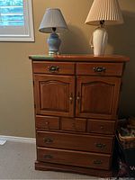 Full view of solid wood dresser with four drawers and two doors, two table lamps on top