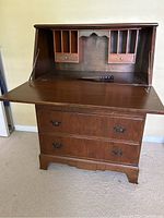 Full open view of the secretary desk showing fold-down writing surface, internal vertical compartments, and two small drawers.
