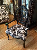 Front angled view of the armchair showing seat and back upholstery, carved wood frame, and armrest details.