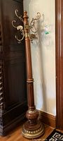 Full view of freestanding wooden coat tree with brass scroll hooks