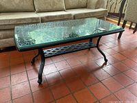 Top view of rectangular glass top coffee table showing thickness and clarity of glass and black metal base with lattice shelf.