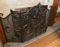 Front view of the three-panel fireplace screen with ornate scrollwork and leaf patterns