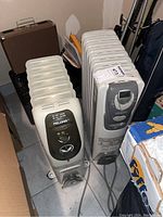 Pelonis and Kenwood oil-filled radiator heaters side by side showing frontal control panels and height.