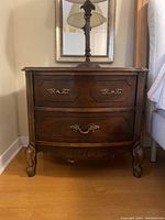 Front view of the wood nightstand showing drawers and brass handles