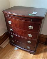 Front three-quarter view of nightstand showing four bowed drawers and oval metal pulls