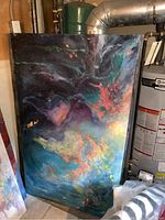 Full view of one of the large abstract paintings leaning against basement wall showing vibrant colors and dynamic abstract design.