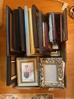 Box filled with assorted picture frames stacked upright showing variety of colors, sizes, and styles