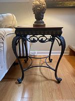 Front view of the side table showing the ornate metal legs and wooden top.