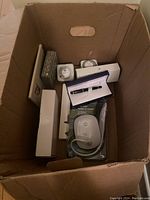 Top view of carton with boxed items including Waterman pen, desk lamp, timers, and other office supplies.