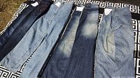 Four pairs of men's Large Means jeans laid out flat showing full length of legs and different denim washes.