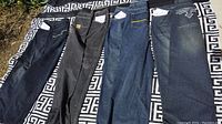 Four pairs of men's jeans laid out flat, showing various denim washes and slight fading.