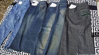 Four pairs of men's jeans laid flat side-by-side showing front leg and pocket details.
