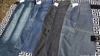 Four pairs of men's jeans laid flat showing different denim washes and styles, highlighting pockets and hems.