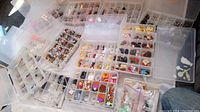 Overview of multiple plastic organizers opened, showing assorted small beads, charms, clay craft pieces sorted into compartments.