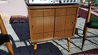 Front view of the vintage wooden stereo cabinet showing panel design and brass knobs on sliding doors.