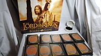 Overview of Lord of the Rings board game box, 10 stacks of Magic: The Gathering cards and Zales ring in box