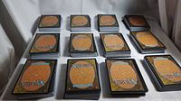Twelve stacks of Magic The Gathering cards, approximately 50 cards per stack, backs showing standard Magic card design.