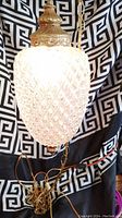 Full view of the lamp showing the textured crystal glass shade and hanging gold chain with cord and switch attached.