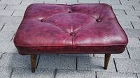 Top angled view of red vinyl footstool showing tufted pattern and textured surface