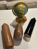 Front view of the antique tin toy globe and three pottery bottles on a white surface.