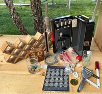 Full view of multiple vintage bar and kitchen items including bottle capper, spice rack, date blocks, assorted bottle accessories and glasses.