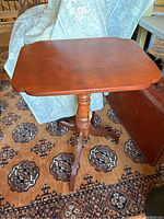 Front side view of the small vintage wooden stand showing top surface and leg detail.