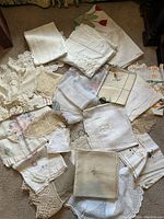Doilies and linens spread on surface showing embroidered pieces, lace doilies, and runners.