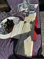 Photo showing liquid silver sterling necklace with long fringe chains and black stones displayed on a white cloth with other decorative items and photos nearby.