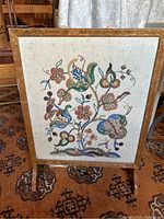 Full view of the fire screen showing embroidered floral fabric within wood frame