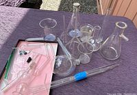Overview of the assorted laboratory glassware including flasks, beakers, tubes, and rods laid out on a surface