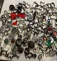 Wide view of mixture of vintage cookie cutters and donut presses laid out on a surface, showing many designs including animals and geometric shapes.