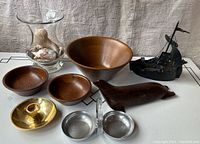 Lot overview including carved seal, wooden bowls, brass candlestick, chrome nut dish, shell vase, and Viking ashtray.