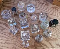Top-down view of collection showing variety of glass inkwells and ink bottles with some lids.