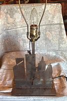 Front view of metal lamp with New York skyline shapes, showing bulb holder and harp frame.