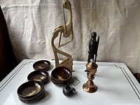 Photo of entire lot showing all carved statues, bowls, lamp and sieve from an angled view