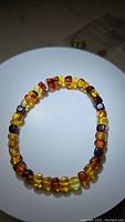 Full view of a Baltic amber bracelet showing gradient amber colors on a white background.