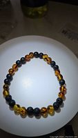 Top-down image of the Baltic amber and lavastone stretchy bracelet showing the contrast between translucent golden amber beads and matte black lavastone beads.