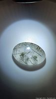 Photo of oval cabochon black rutilated quartz gemstone displayed under direct light showcasing black needle inclusions and high polish.
