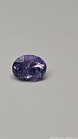 Close-up photo of the oval cut tanzanite gemstone showing its purple color and facets.