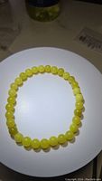Top view of the lemon jade bead bracelet showing smooth, round, yellow beads on stretchy elastic.