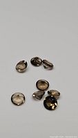 Seven small natural smokey quartz gemstones arranged on a plain light background.