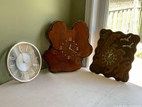 Three clocks displayed side by side near a window showing front and side views.