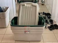 Four stacked Rubbermaid RoughTote storage bins with lids, showing size and color.