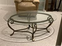 Oval glass top coffee table with brass frame, showing full top and legs.