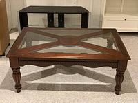 Full view of rectangular wooden coffee table with four triangular glass inserts on top and turned carved legs.