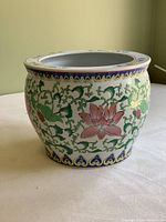 View of the outside of the large porcelain goldfish bowl showing detailed floral and vine pattern with blue and gold trim.