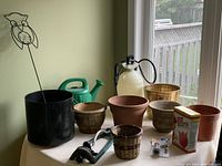 Full lot overview showing various pots, watering can, owl garden spike, sprayer, and some flower box holders.