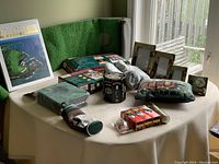Table with multiple golf-related items and home decor including indoor putting mat, new balls, cups, tees, club covers, ball carrier, photo frames, clock, and training kit.